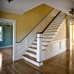 Straight stair with box newels and wood balusters. Stair features paneled wainscoting.