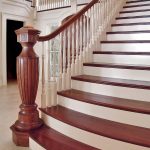 Grand staircase with a large intricately custom carved newel post. Stair flairs at its base and features mahogany treads and railing.