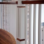 Balcony in a residential home showing square wood balusters, a box newel, and curved railing..