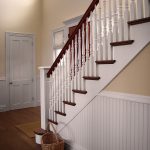 Straight stair with box newels and wood balusters. The stair features beadboard wainscoting.