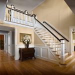 Straight stair with box newels and wood balusters in a grand foyer. Stair features a large balcony.
