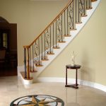 Curved staircase with wrought iron balusters and over-the-post railing.