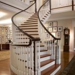 Curved unsupported staircase with wood balusters in a grand foyer.