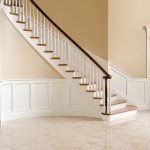 Curved staircase with paneled wainscoting, wood balusters, and over-the-post railing.