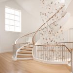 Grand multi-level stacked unsupported curved staircase with steel balusters in a modern home.
