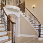 Double curved stair with wrought iron balusters in a grand foyer.
