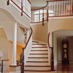 Curved staircase with custom turned newel posts and wood balusters in a grand foyer.