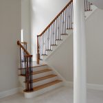 Straight scissor stair with wrought iron balusters and over-the-post railing.