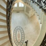 Dramatic curved stair with custom wrought iron balusters and stone treads and risers.