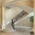 Dramatic curved stair with custom wrought iron balusters and stone treads and risers.