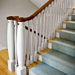 Straight staircase with white balusters and custom turned newel posts.