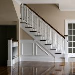Straight stair with box newels and wood balusters. Stair features paneled wainscoting.
