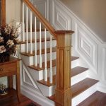 Straight stair with box newels and wood balusters. Stair features wood paneling wainscoting.