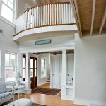 Grand foyer in a coastal home. A curved balcony features wood balusters and a curved railing.