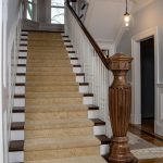 Stair with a grand custom carved newel post and wood balusters.