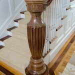 Stair with a grand custom carved newel post and wood balusters.