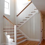 Scissor stair with wood balusters and square newel posts. The newel posts feature a round custom cap.