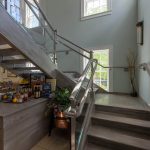 Commercial staircase with glass railing and open risers. ADA compliant handrail.