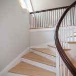 Curved winding staircase with wood balusters and a curved handrail.
