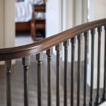 Custom curved preassembled staircase with white oak treads and scotia, primed butress style stringer, primed risers, custom bronze balusters, and 6014 sapele mahogany rail.