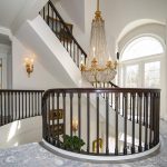 Custom curved preassembled staircase with white oak treads and scotia, primed butress style stringer, primed risers, custom bronze balusters, and 6014 sapele mahogany rail.